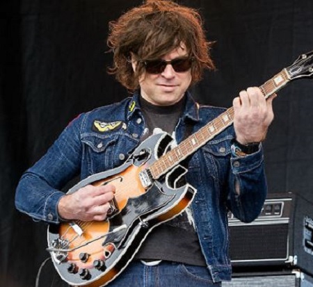 Ryan Adams playing guitar while in concert
