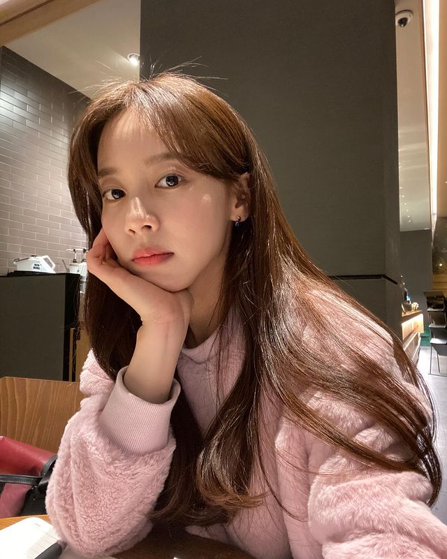 Selfie picture of Ji-hee Hong wearing pink sweater sitting in cafe