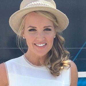 Photo of Carolyn Manno  wearing a white t-shirt and a coffee-colored hat and a diamond top in an ear.