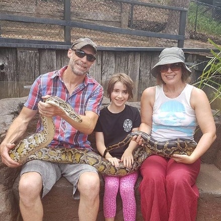 Steve Le Marquand posing by carrying python and wearing green cap, mixed color t-shirt. 