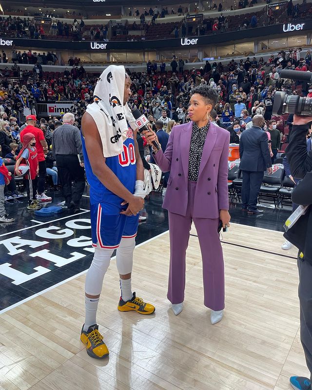 Monica Mcnutt reporting by wearing purple suit.