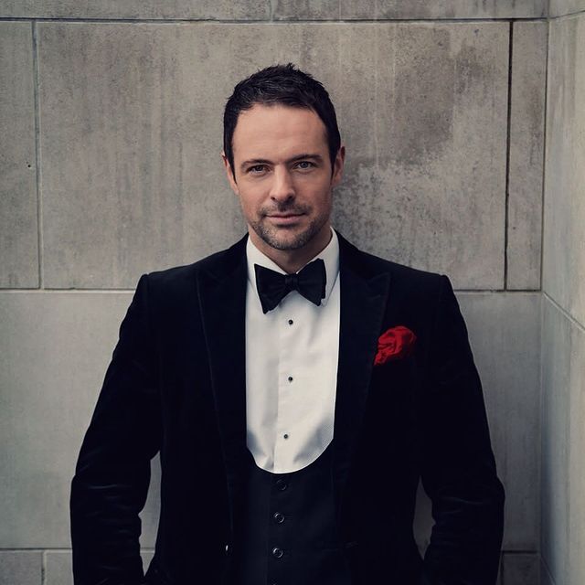 Matthew Dowden posing for a photoshoot by wearing black suit.