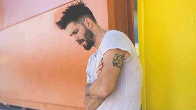 Casey Jon Deidrick posing for a photoshoot showing his tattoos