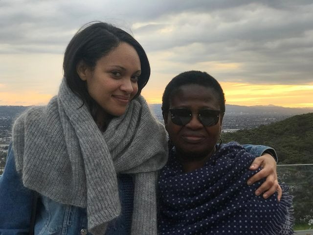 Cynthia is wearing a blue jeans coat and silver color Moflor and her mother is wearing a shal with white box designed.