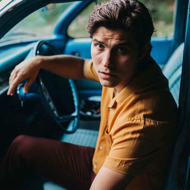 Luke Bilyk posing by wearing yellow t-shirt and red pant.