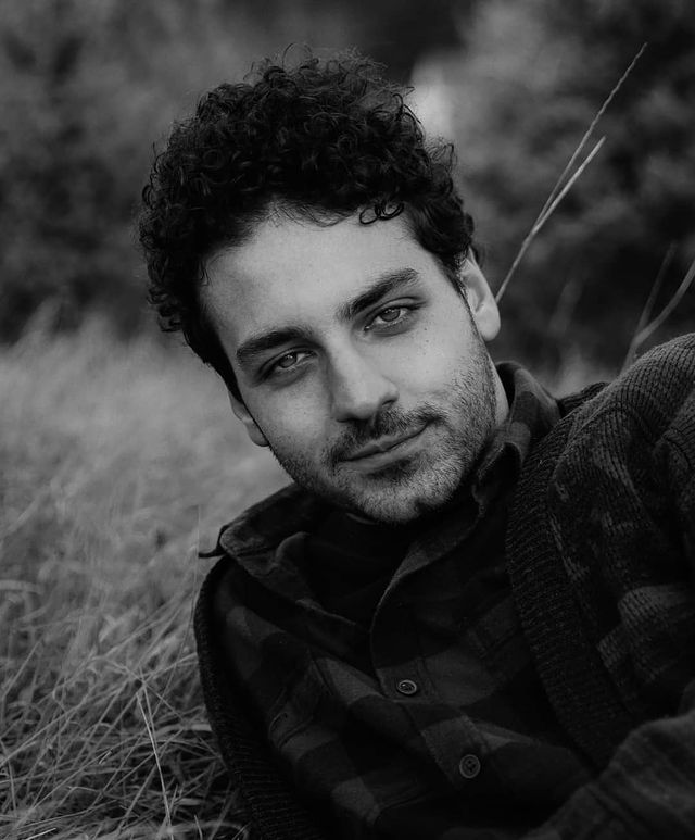 Ehren Kassam posing by wearing t-shit and a black vest.