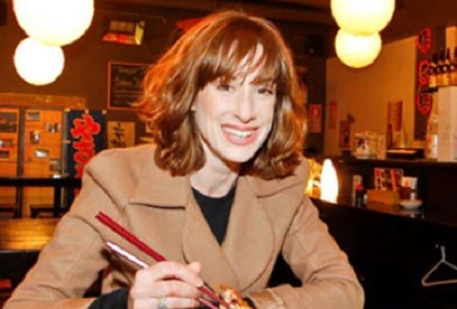 Miranda in a light brown coat and black t-shirt inside it.