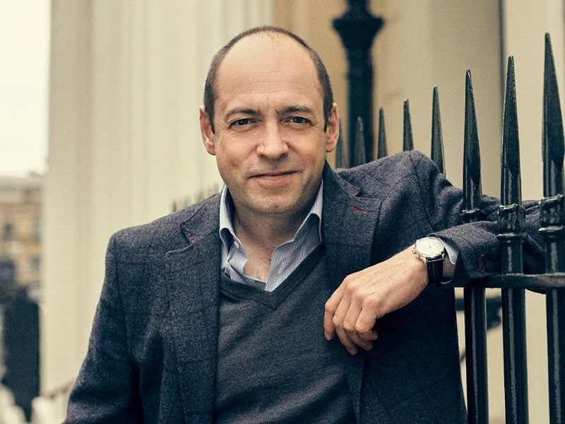 Gareth Neame  was captured wearing sweater, coat and posing for the photo  with his one hand in the wall