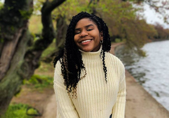 Trinitee Stokes with posing for the photo with a black curly hair and wearing high neck