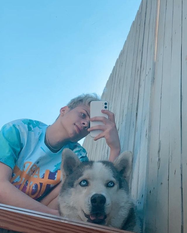 Picture of Chris Daniels posing for a photoshoot with his dog wearing blue t shirt