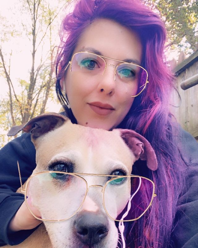 Picture of Jenna Morasca posing a for a photoshoot with her dog wearing glasses