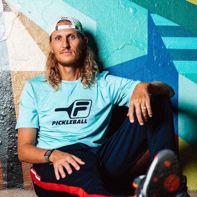 Picture of Tyson Apostol posing for a photoshoot wearing blue color dress and white cap