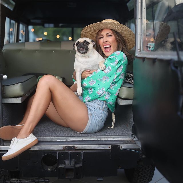 Picture of  Erin Coscarelli with her pet posing for a photoshoot wearing hat and short jeans