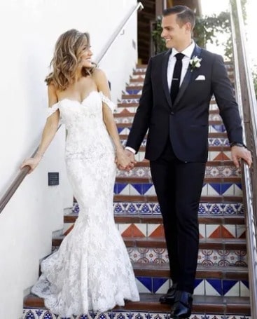 Picture of Erin Coscarelli with her husband Jonathan Chironna posing for a photoshoot in a wedding dress wearing white color gown and black color blazer