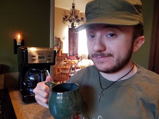 Picture of Atticus Shaffer posing by wearing a green outfit.
